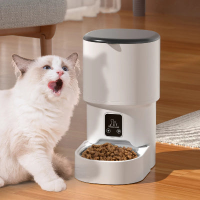 Cat interacting with an automatic pet feeder on a wooden floor.
