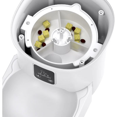 White pet food dispenser with compartments containing small food pieces on a white background